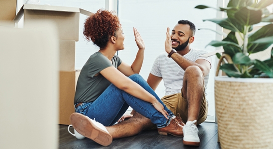 Couple high-fiving while sitting near boxes.