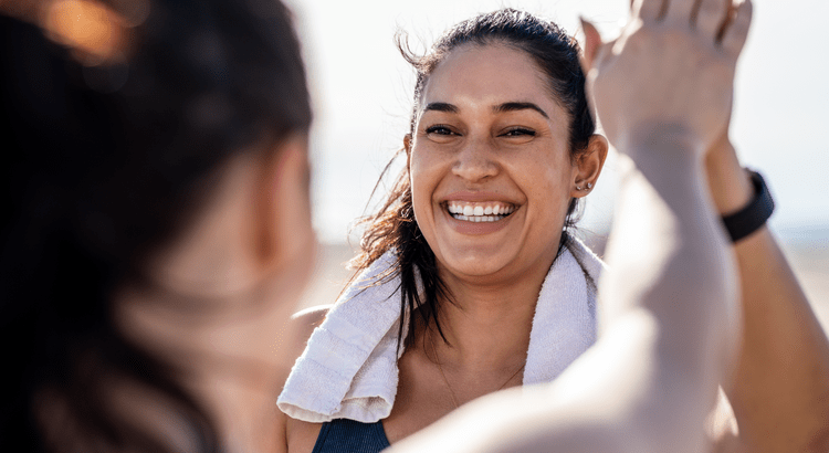 A happy woman smiling with a towel draped over her shoulders.