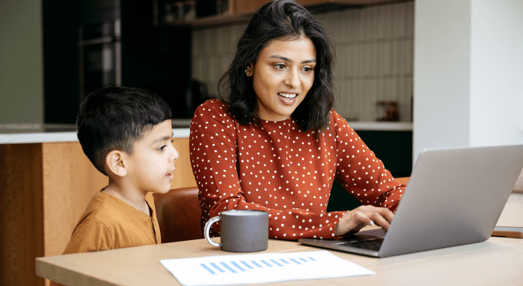 Woman teaching young boy using laptop, papers nearby.